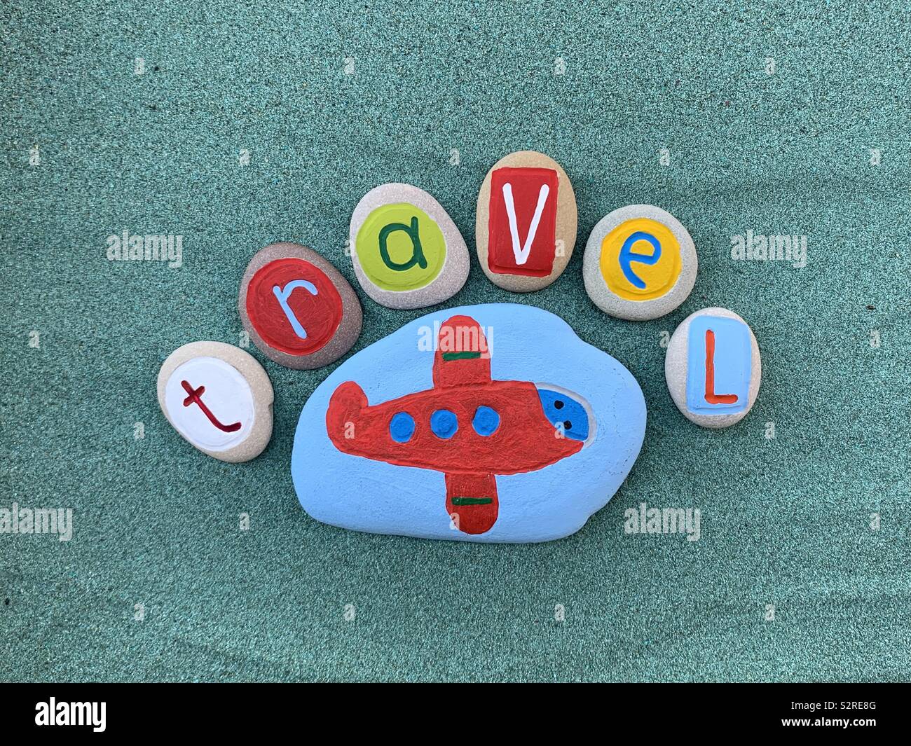 Travel logo with colored stones over green sand Stock Photo