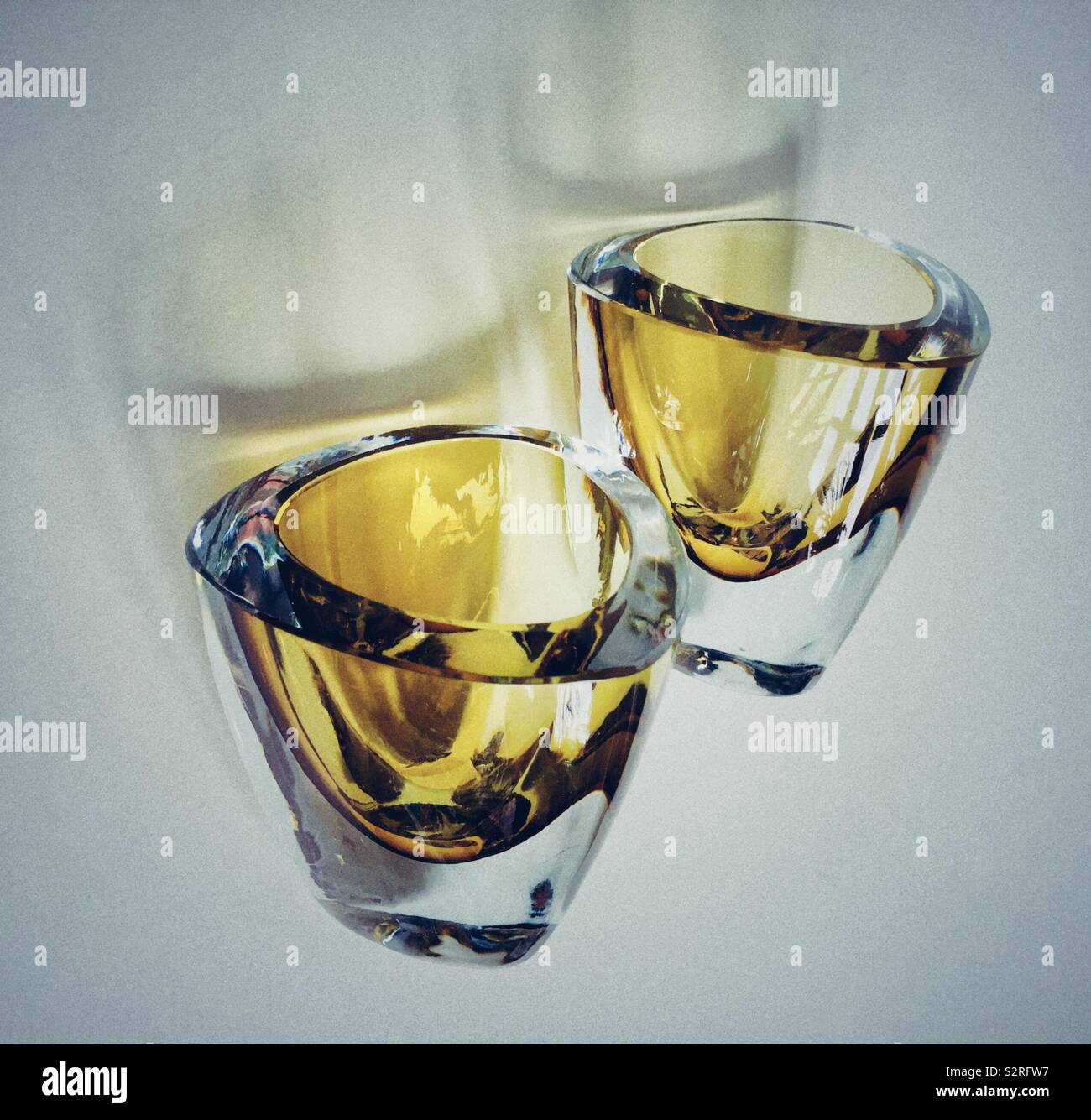 A pair of sturdy vintage smoked glass tumblers  caught tumbling in space - Smartphone Captured Stock Image