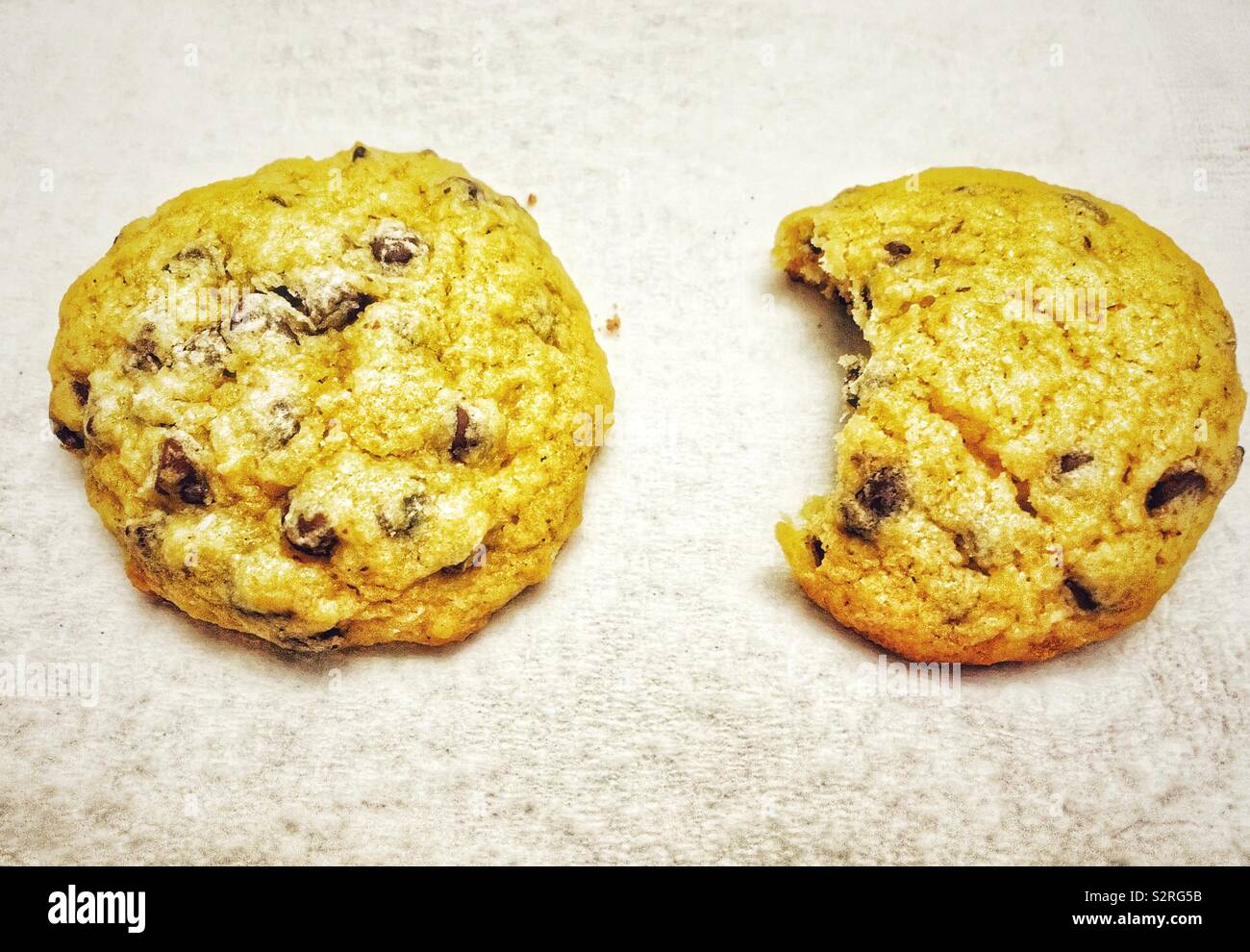 Chocolate chip cookies, one whole cookie and one with a bite out of it - Smartphone Captured Stock Image