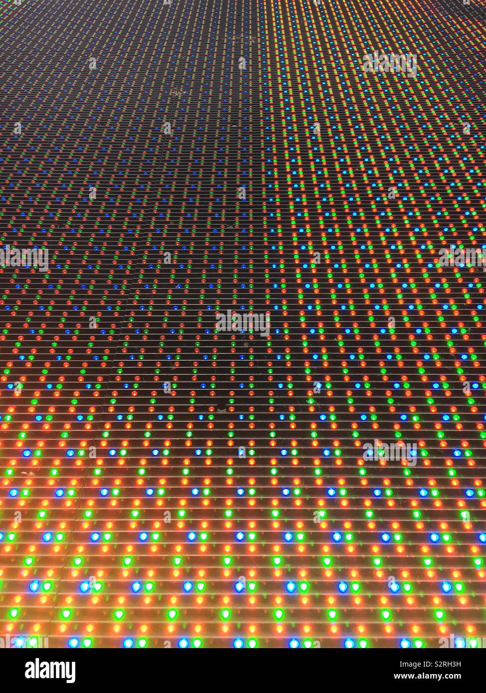 Huge matrix computer screen rolling with blue, gold, and green dots. - Smartphone Captured Stock Image