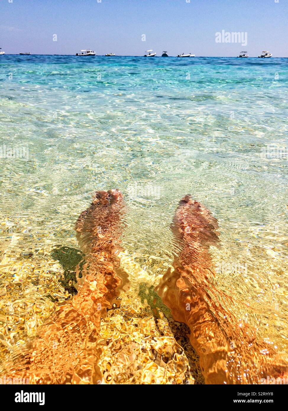 Relaxing and cooling down in a crystal clear sea on a beach in Sardinia Italy on a summer holiday in hot weather - feet selfie - bare summer feet Stock Photo