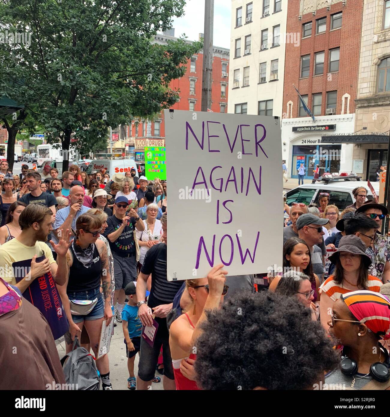 July 2, 2019. A sign at the Close the Camps Rally reads”NEVER AGAIN IS NOW,” Middle Collegiate Church, Manhattan, New York, New York, United States. - Smartphone Captured Stock Image