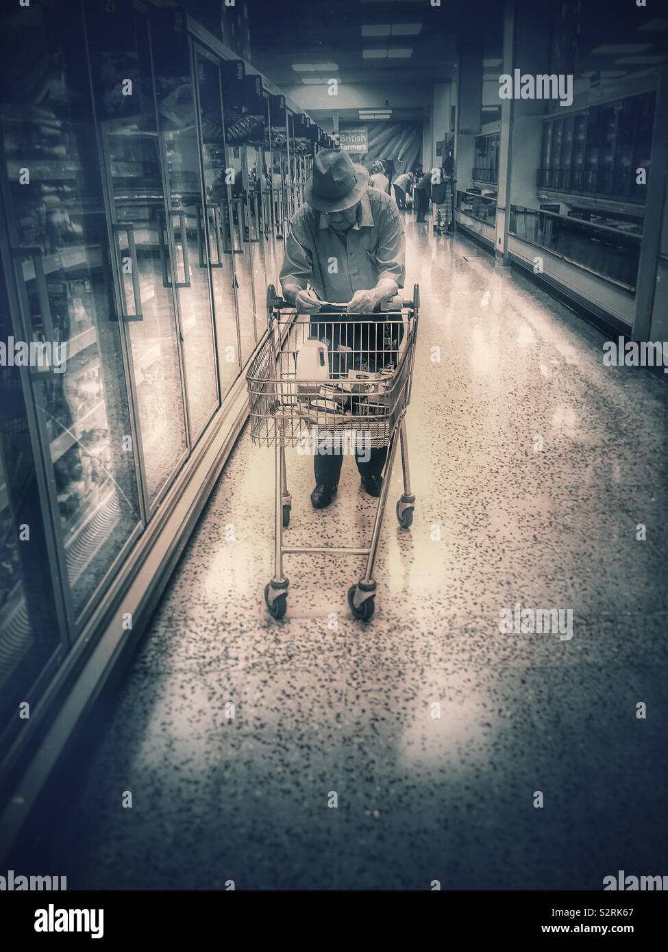 Old man supermarket shopping with his trolley and list . - Smartphone Captured Stock Image