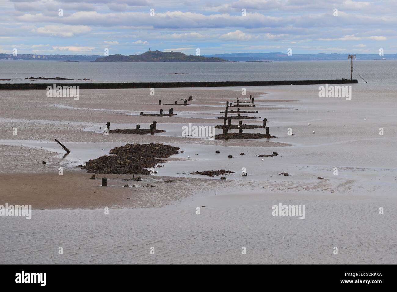 Remains of old pier viewed at low tide Stock Photo