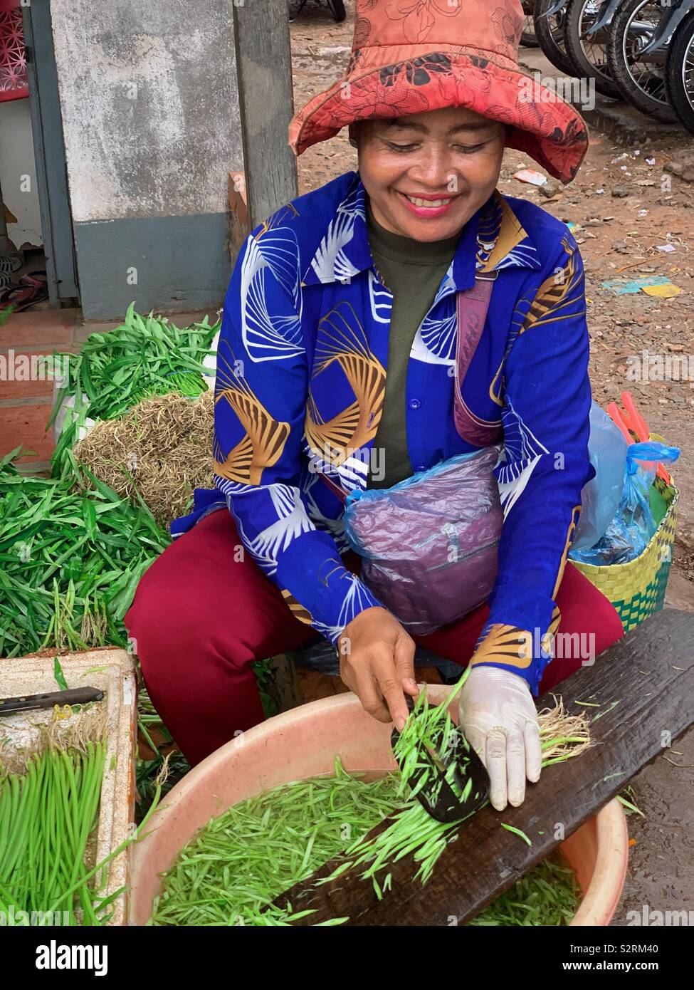 Woman chopping vegetables and smiling at local market in  Siem reap Cambodia - Smartphone Captured Stock Image