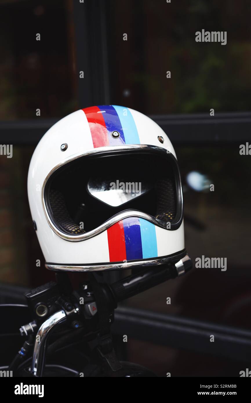 White motorcycle helmet, with red blue and turquoise stripes, hanging on the mirror. Stock Photo