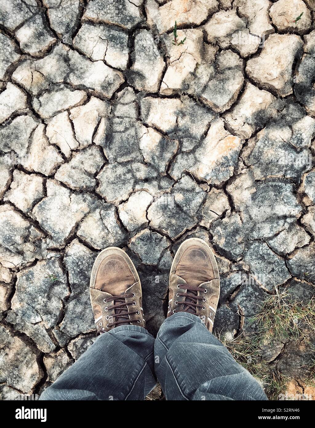 Man's feet standing on parched earth. - Smartphone Captured Stock Image