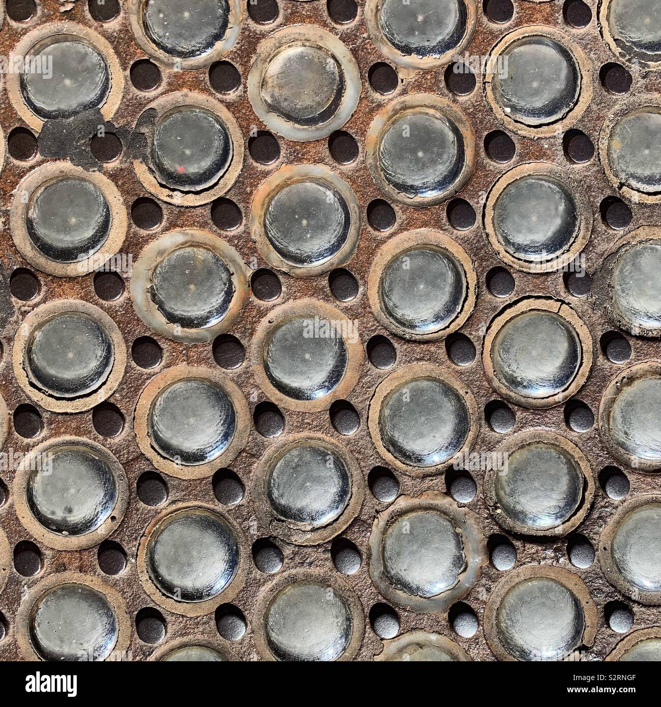 A portion of the sidewalk in SoHo, Lower Manhattan, New York City. In the mid 1800s, light entered subterranean factories through circular vault lights in the sidewalks of SoHo and Tribeca. - Smartphone Captured Stock Image