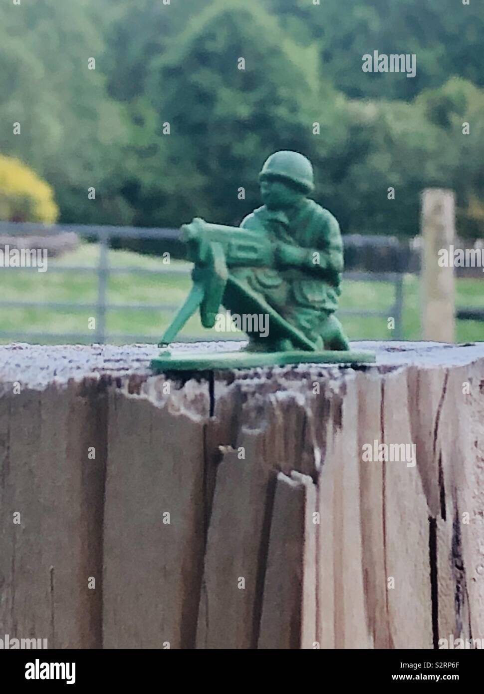 Green toy army man on wood fence post Stock Photo