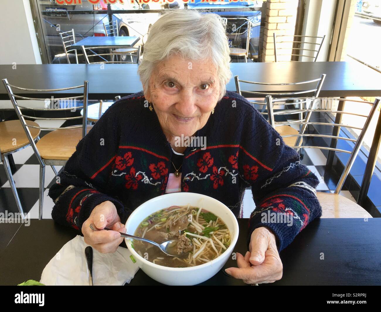 Elderly lady enjoying a bowl of beef pho. Stock Photo