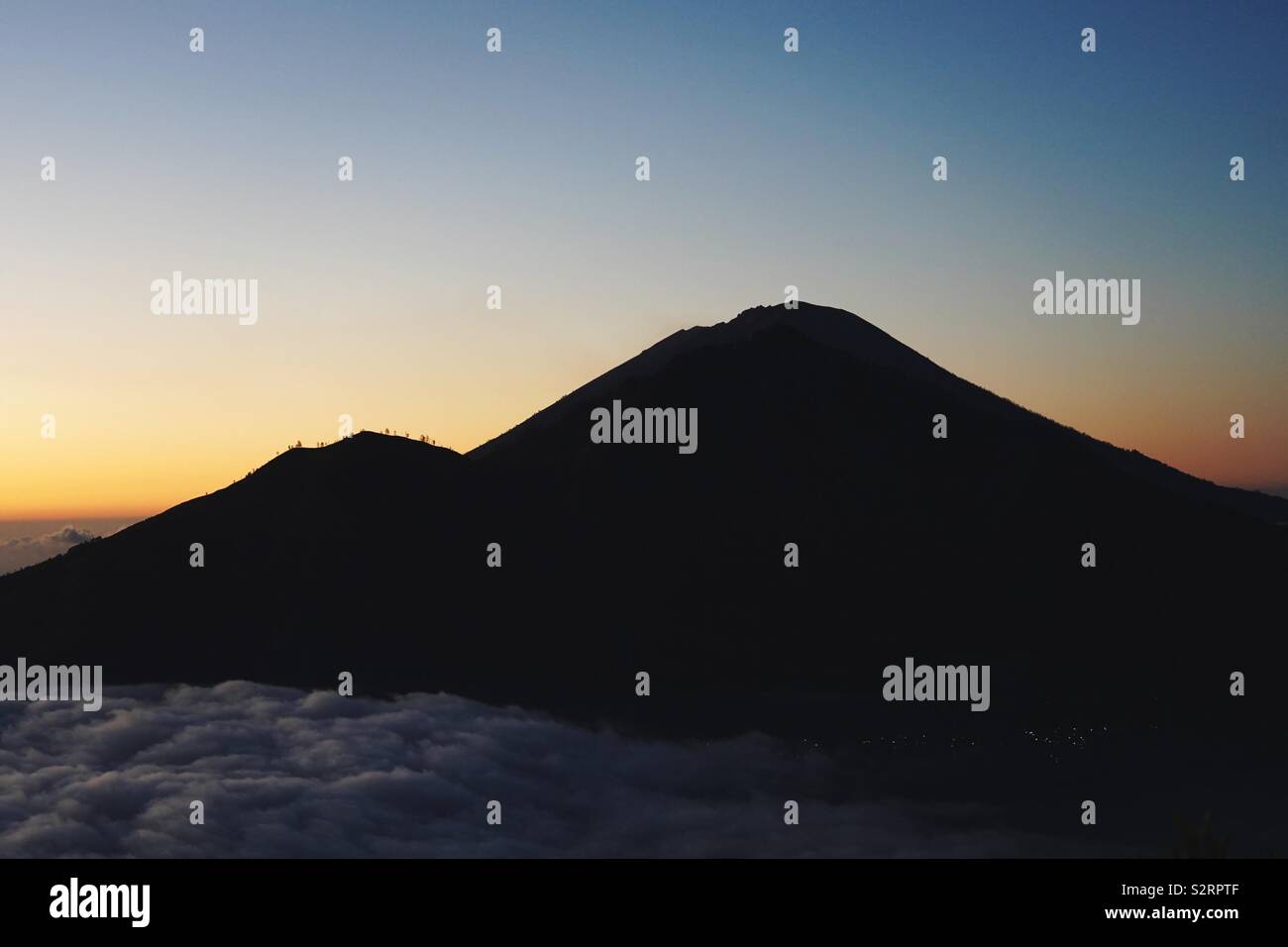 Silhouette of a large vulcano with two distinguished craters on the island of bali, indonesia, in the dawn, by sunrise. Stock Photo