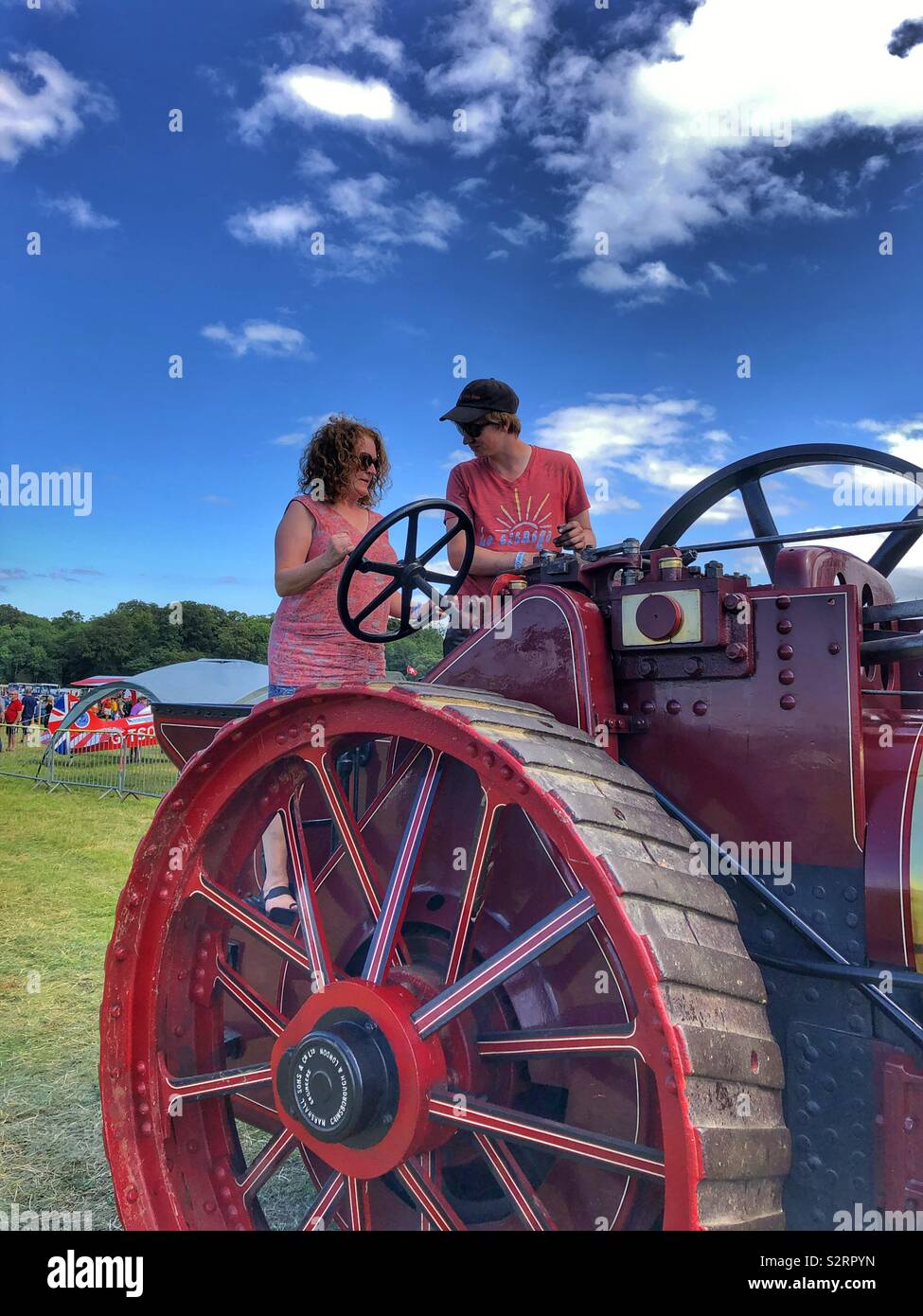 A woman being taught how to drive a steam traction engine at