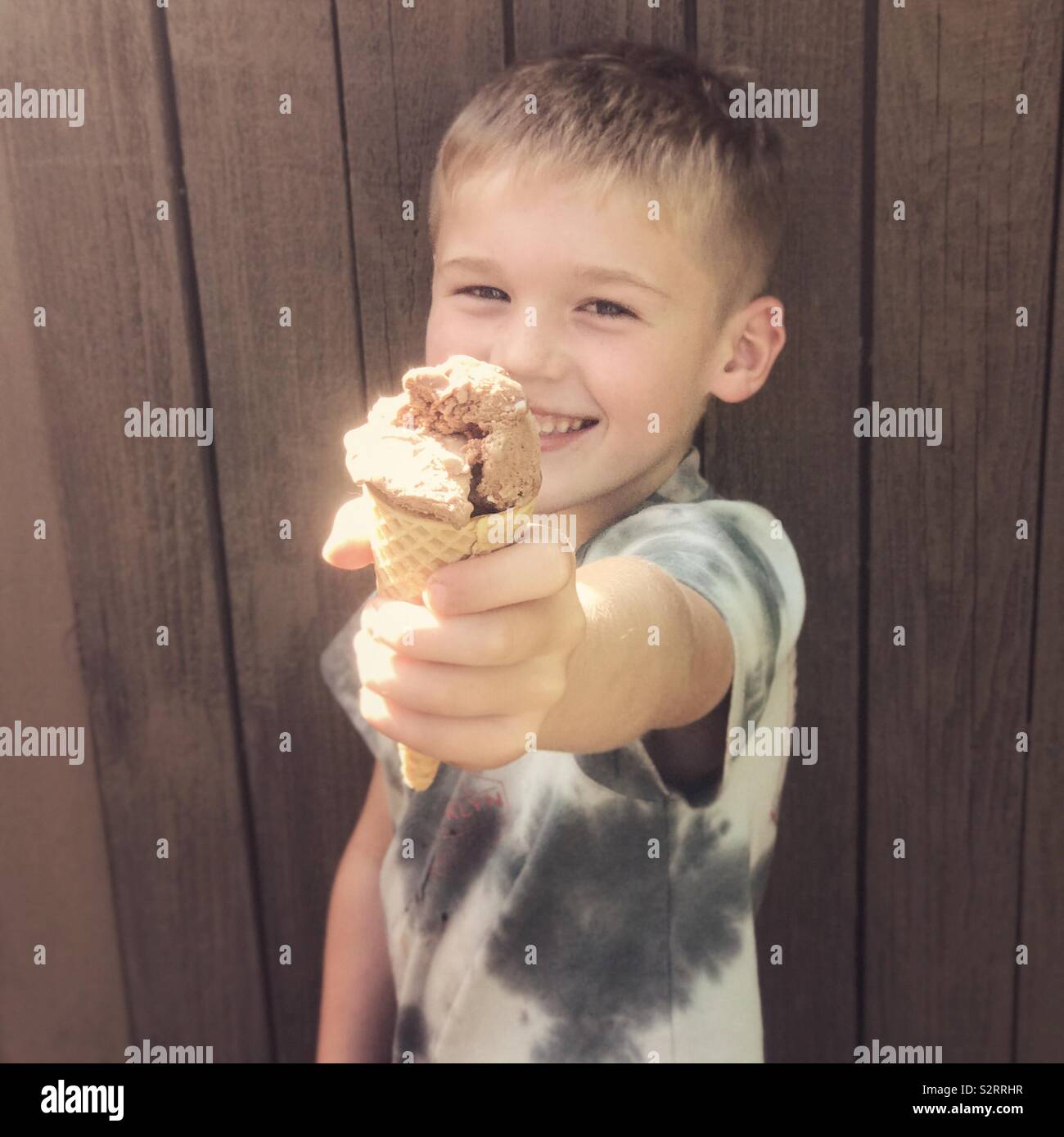 A Young Boy With Blonde Hair And Blue Eyes Holding A Chocolate Ice