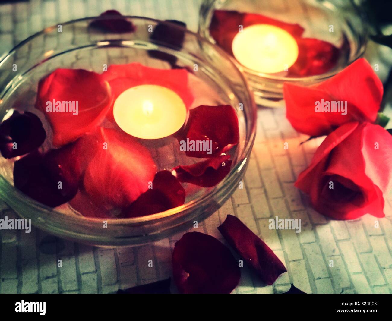 A beautiful ambiance of tea light candles floating in the water with soft  red flower petals , roses Stock Photo - Alamy