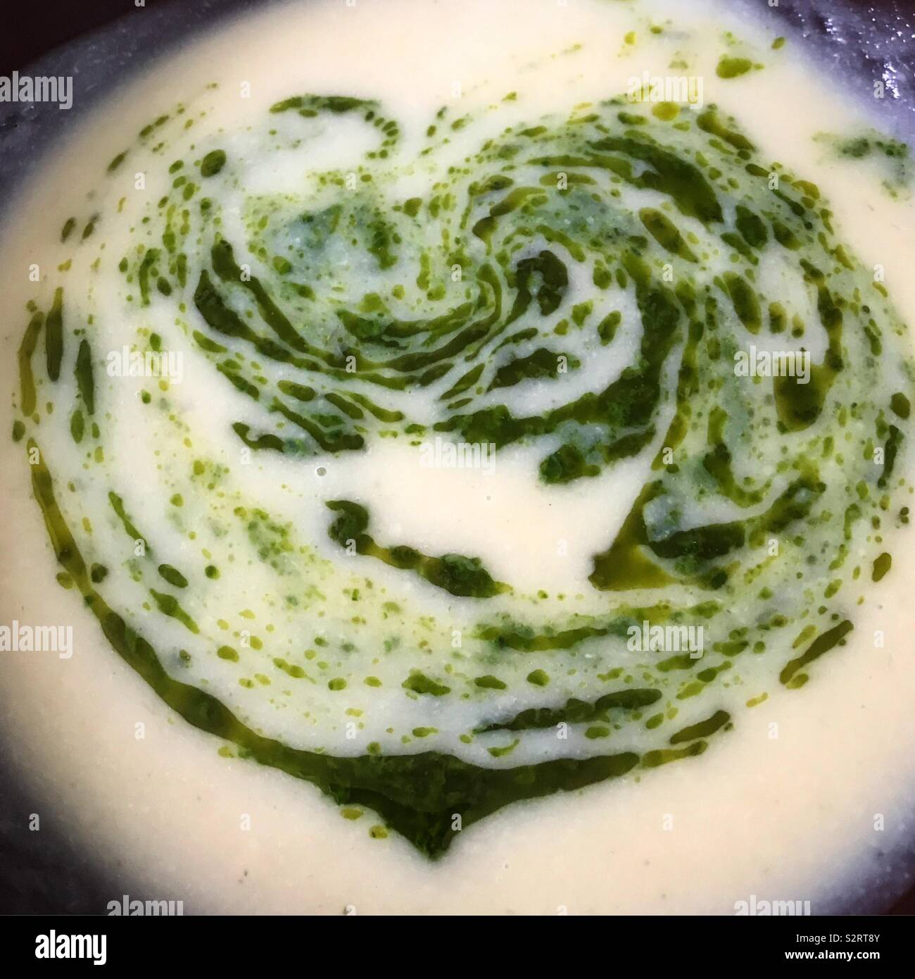 Love food. Vegetable soup with a basil and spinach sauce stirred into the shape of a heart - Smartphone Captured Stock Image