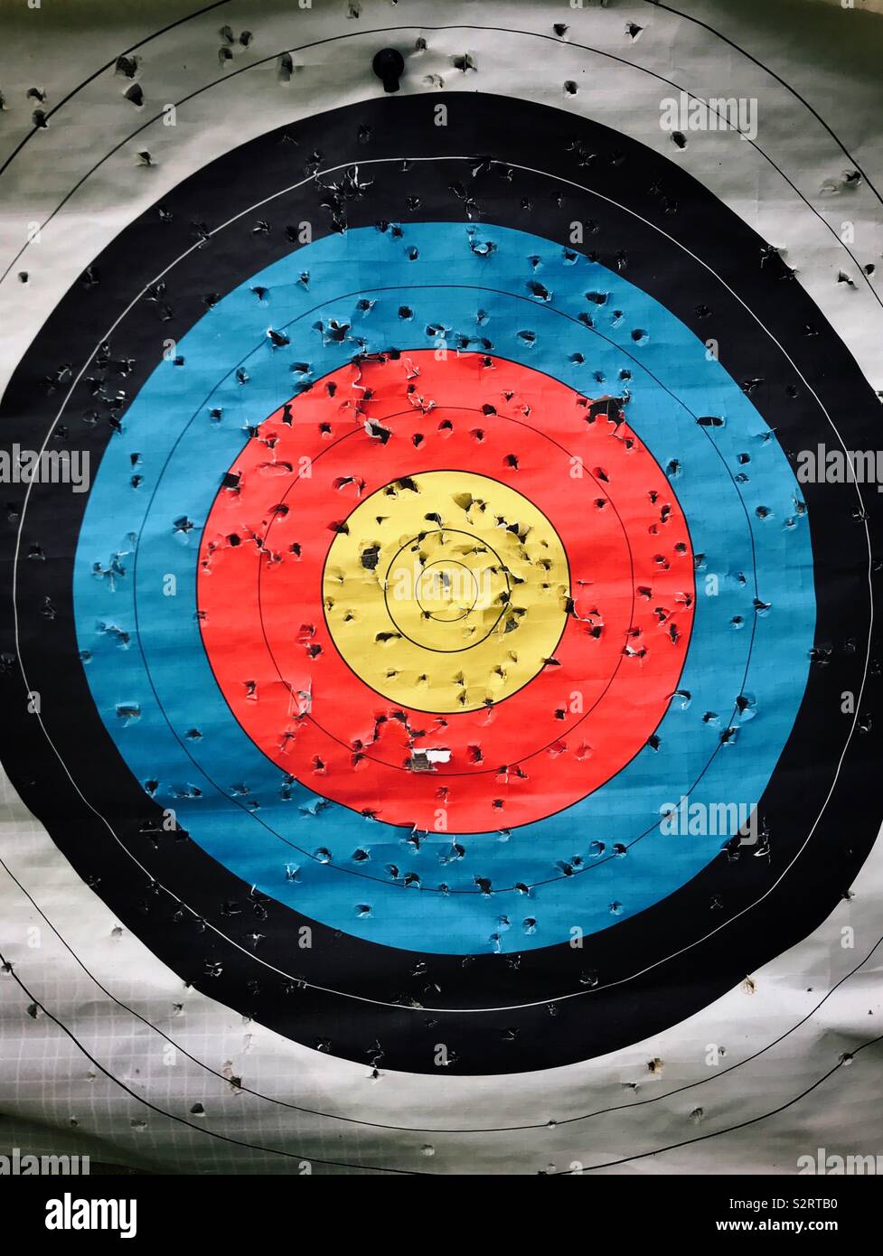 Numerous arrow holes on an archery target. Somebody’s been having fun trying to hit the bullseye! Photo Credit - © COLIN HOSKINS. - Smartphone Captured Stock Image