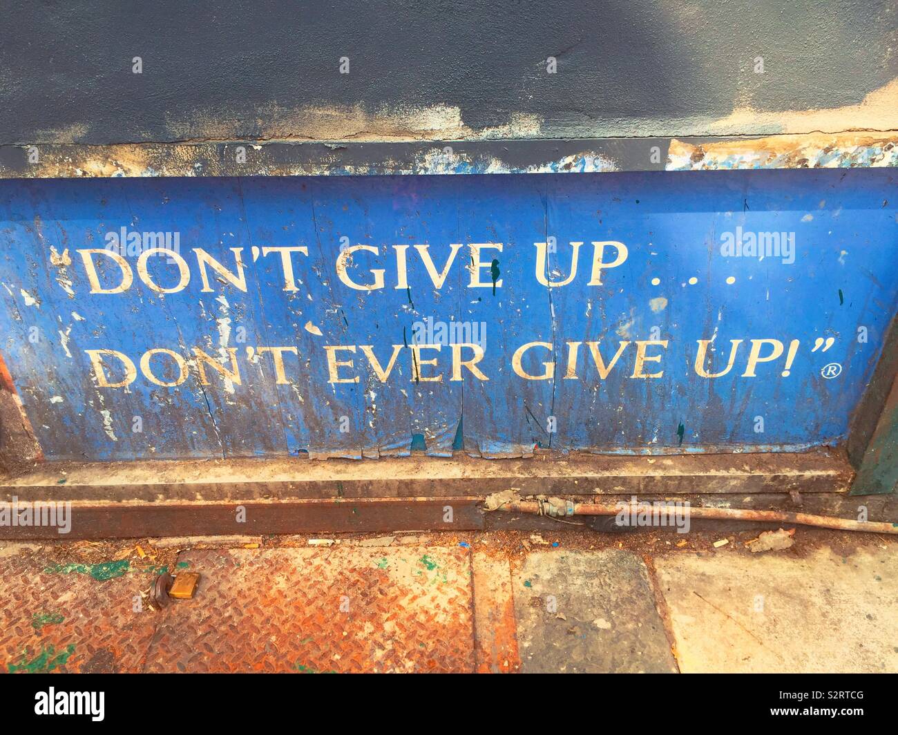 A worn, dirty and rusty sign proclaiming “don’t give up don’t ever give up“, USA - Smartphone Captured Stock Image