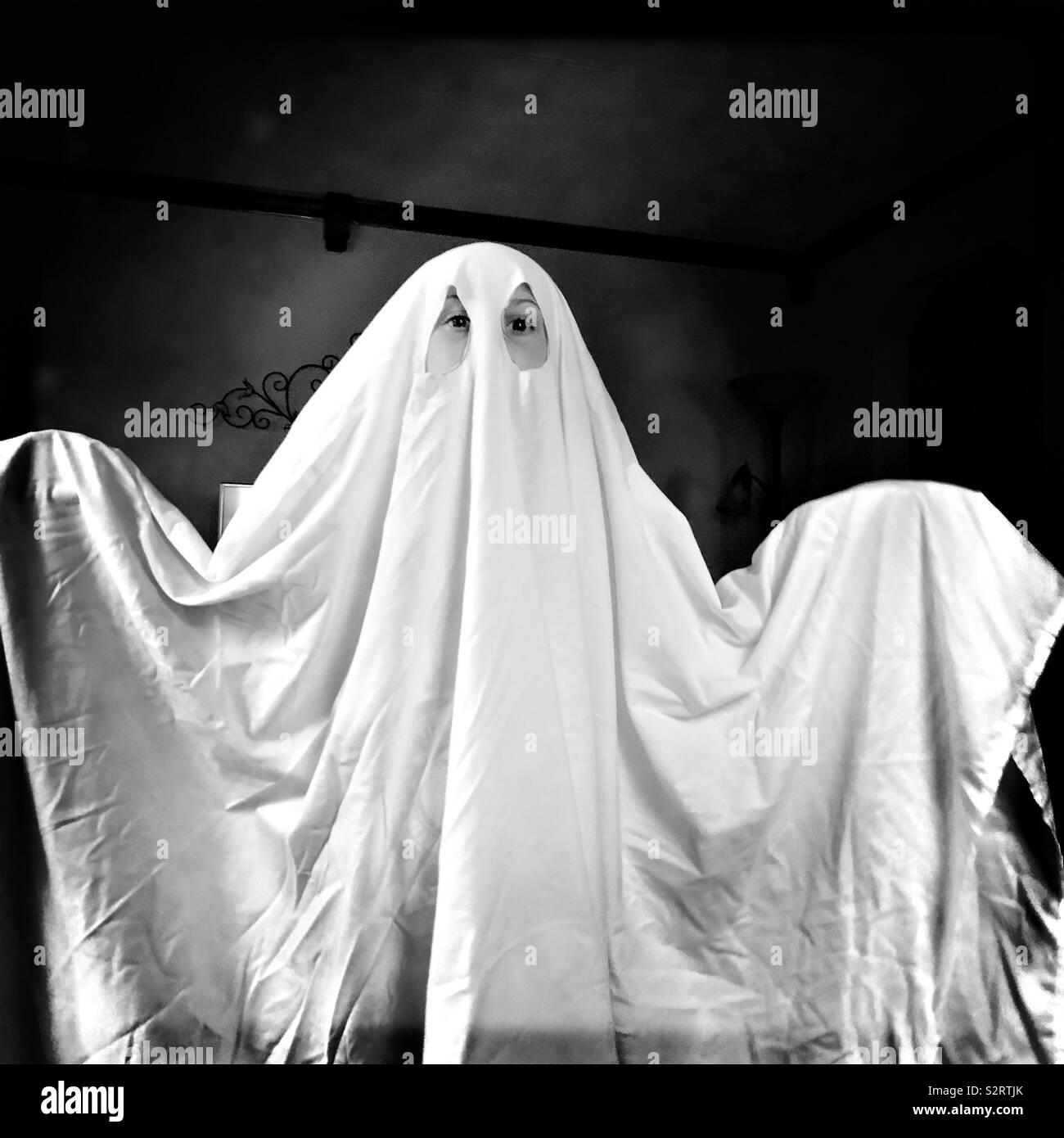 A child wearing a ghost costume made from a white bedsheet. Stock Photo
