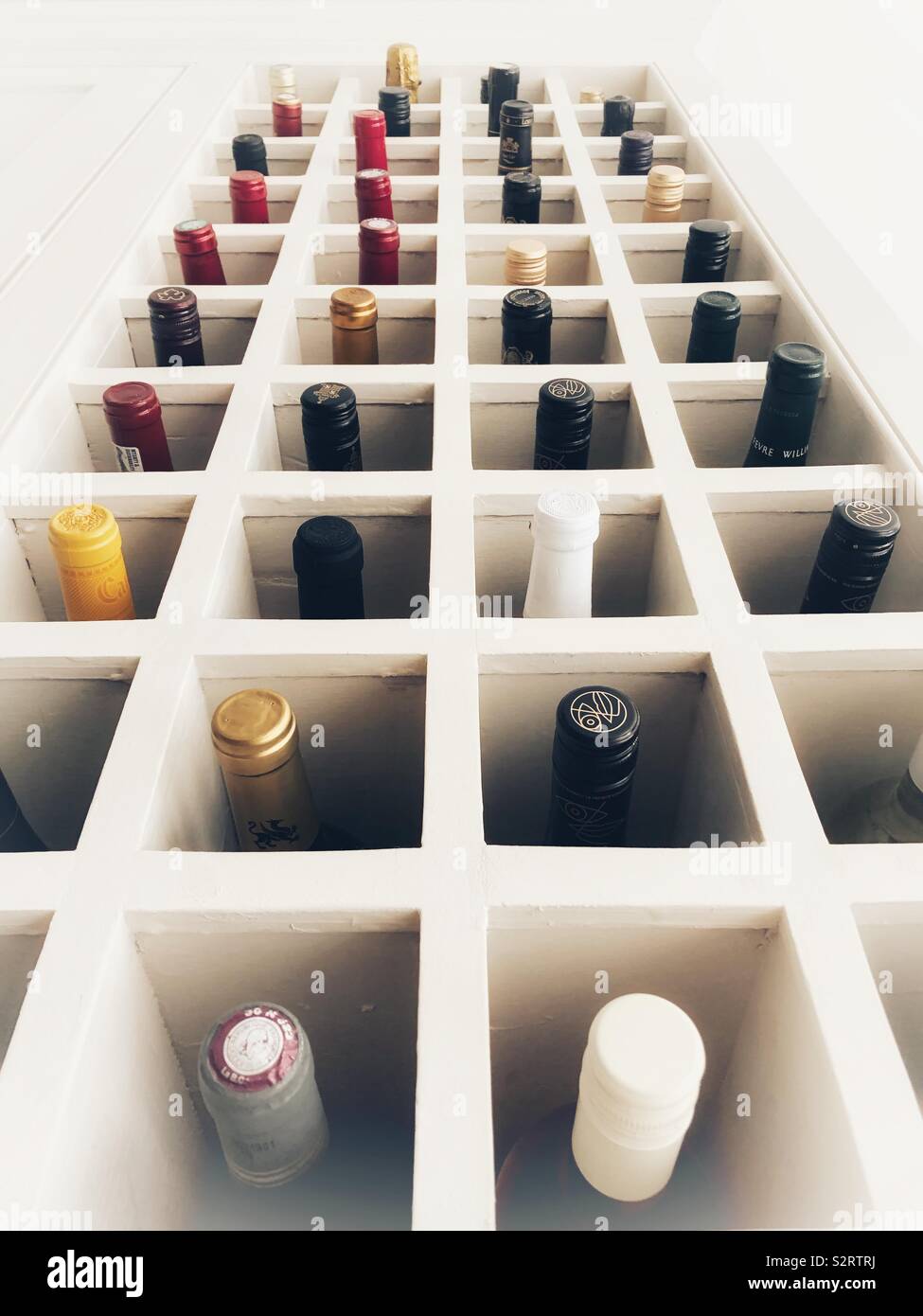 Looking up at many wine bottles in a wooden wine rack. - Smartphone Captured Stock Image