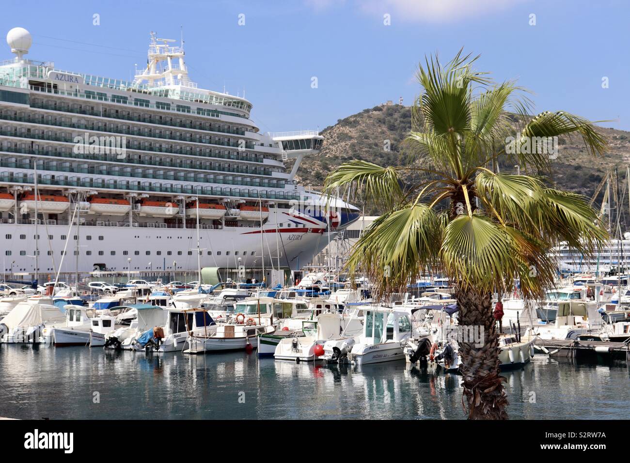 Large cruise ship towering over smaller boats in marina Stock Photo