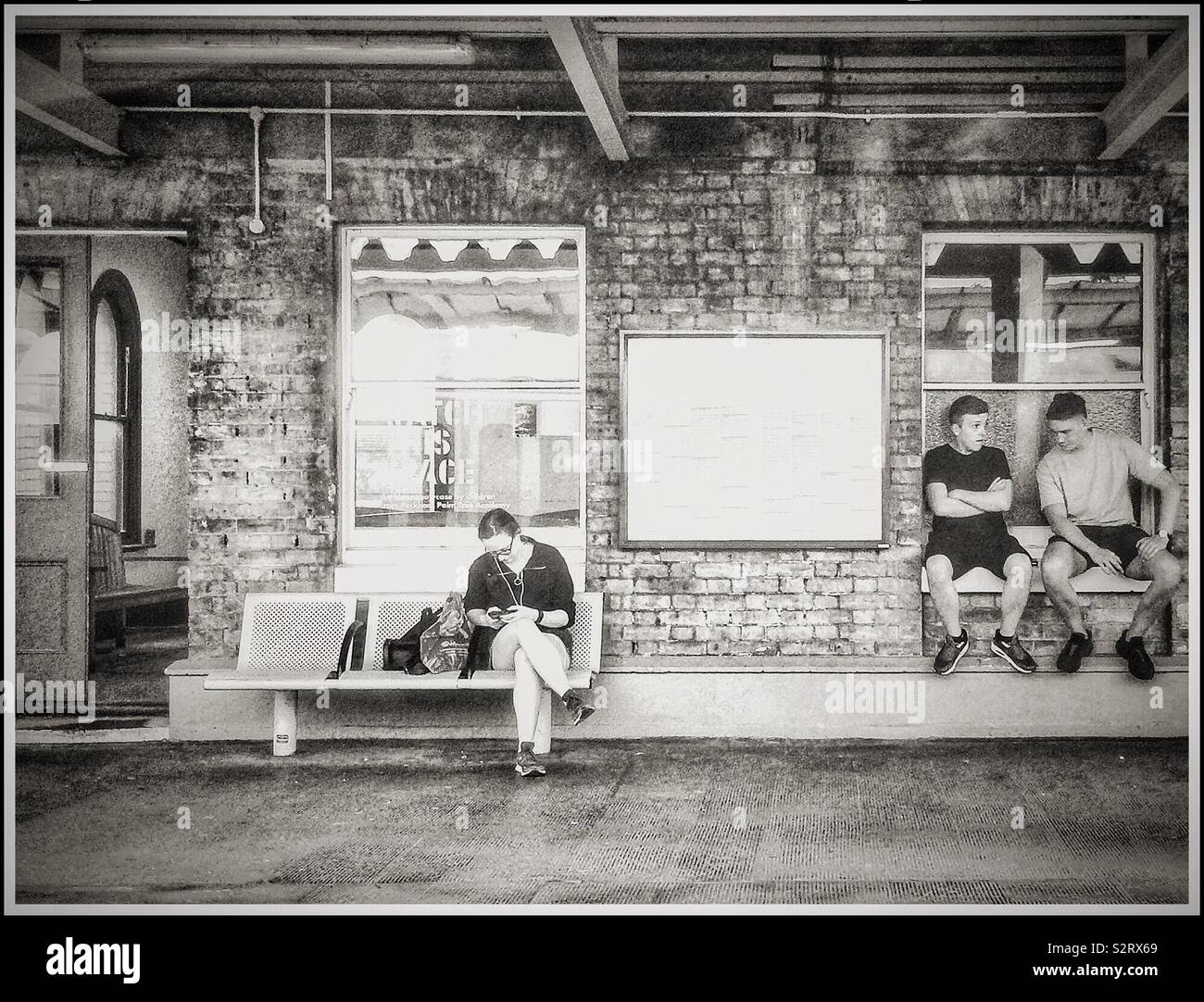 Casual commuters wait for a train at Peckham Rye train station Stock Photo