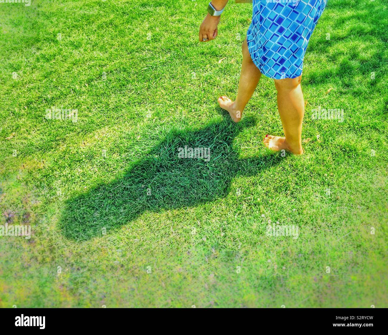 A woman walking barefoot in the grass. Stock Photo