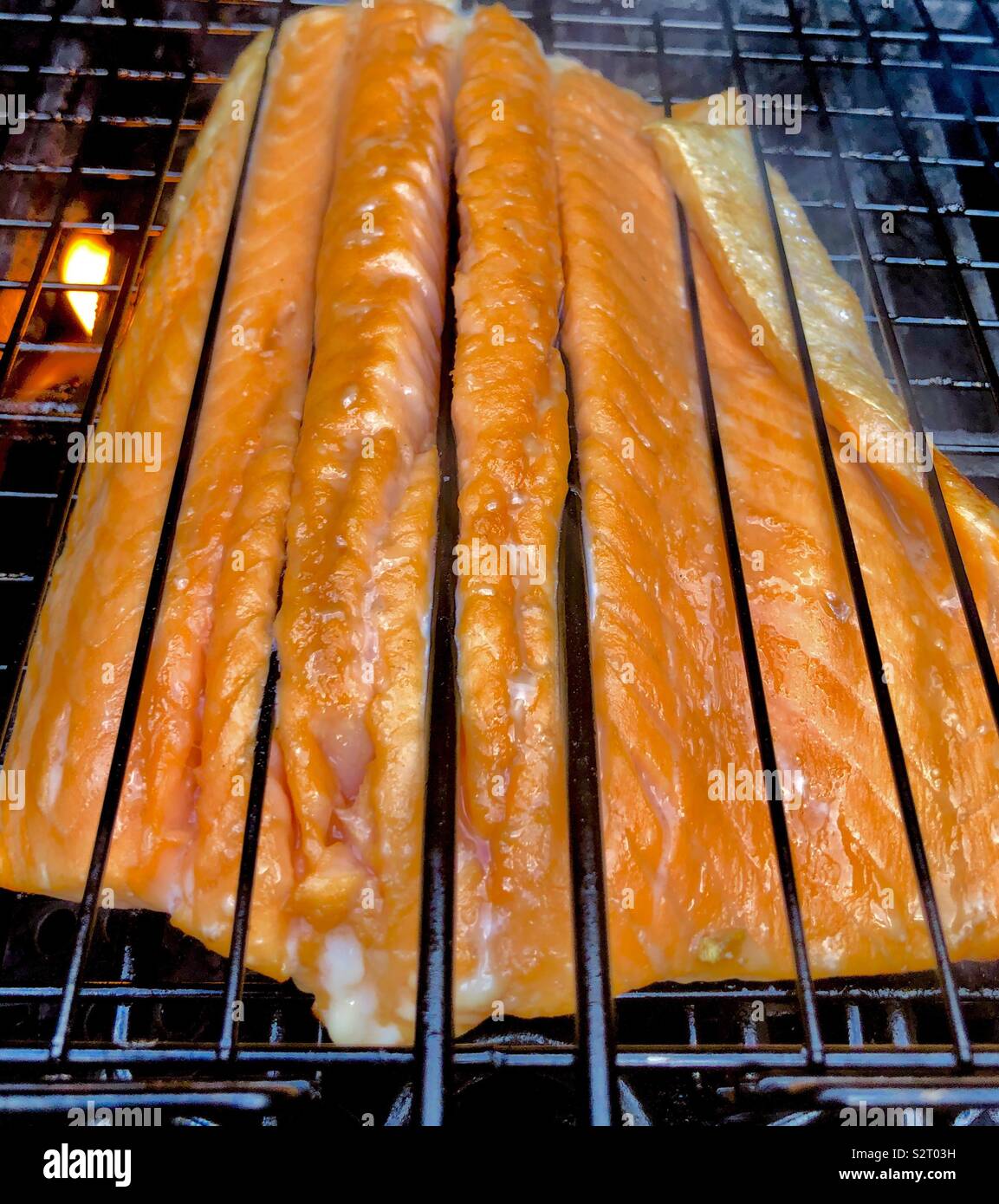 Cooking salmon on a grill with flame Stock Photo