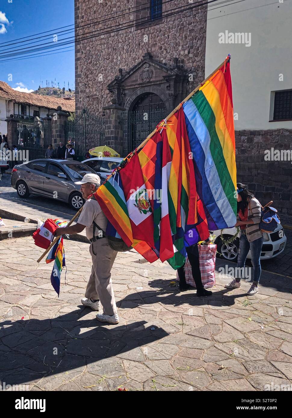 Flag seller carrying flags in Cusco Cuzco Perú Peru. Cusconian flag looks like gay pride flag. Stock Photo