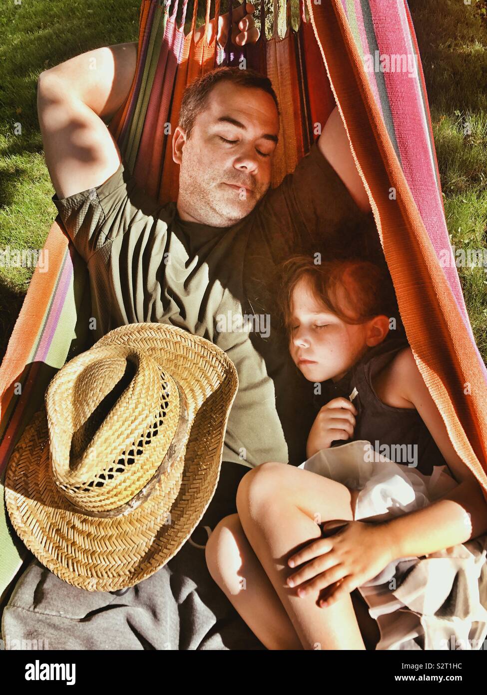 Father and young daughter napping in a hammock in the sun Stock Photo