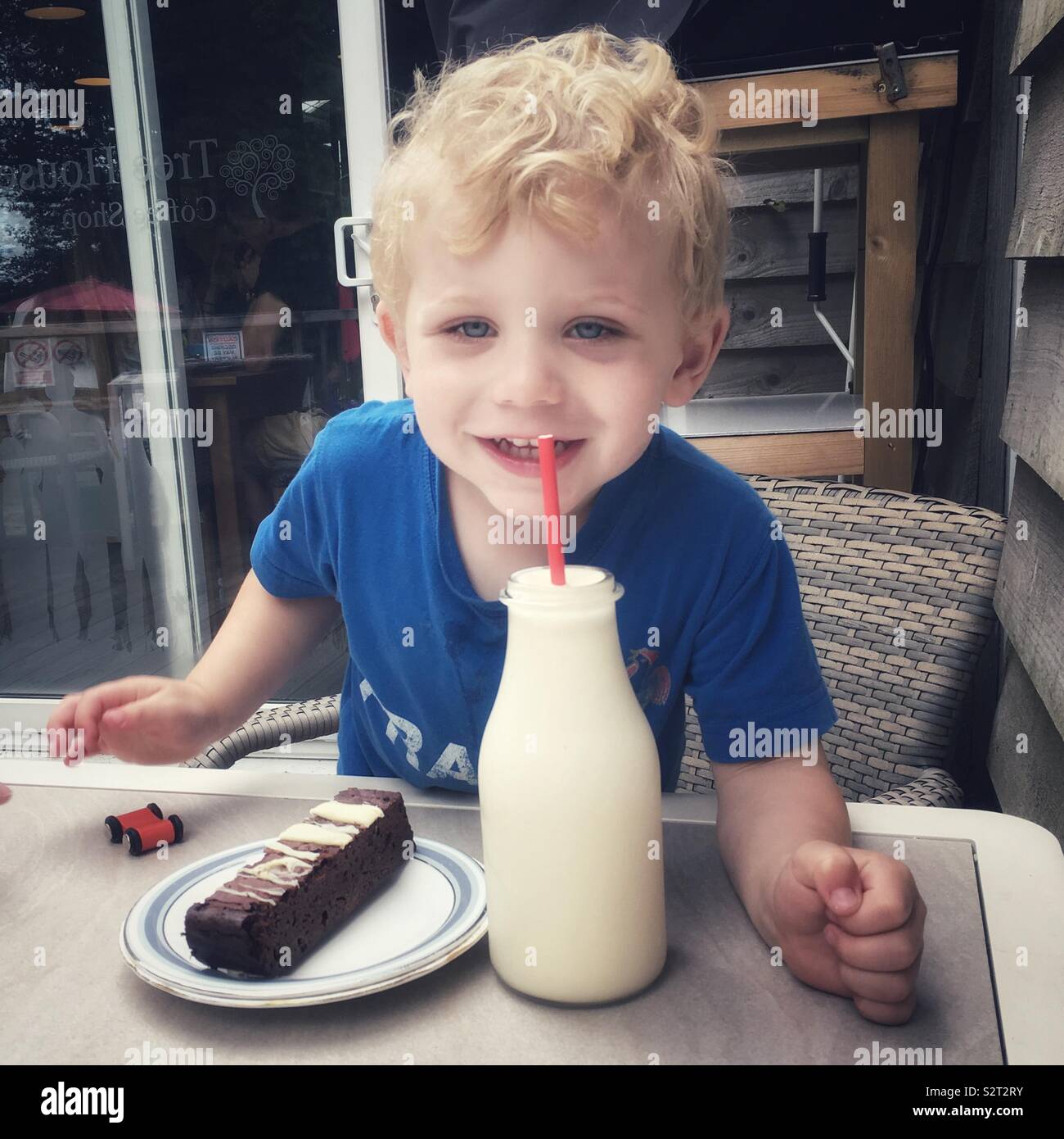 Two year old boy with a vanilla milkshake and a chocolate brownie - Smartphone Captured Stock Image