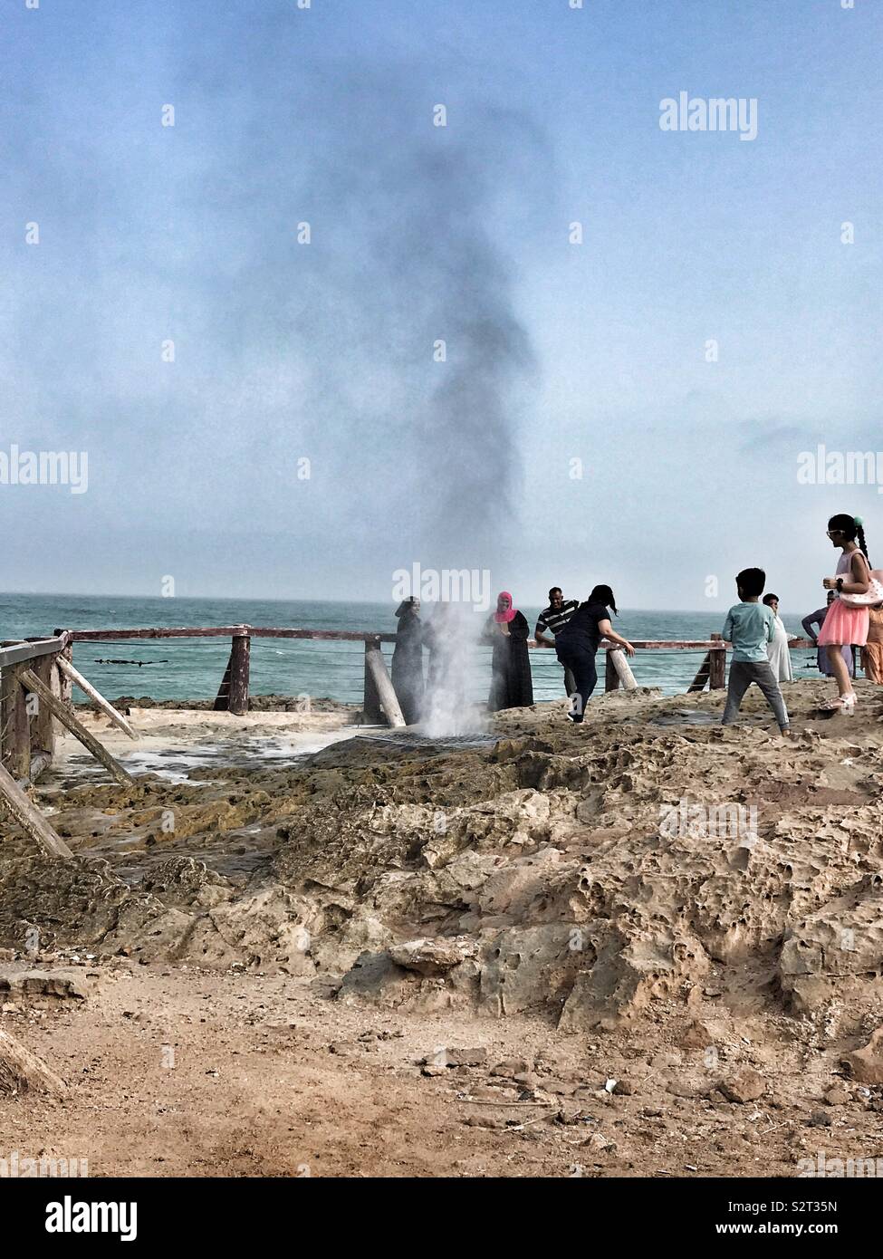 Naturally occurring sea geyser splashing all over with children escaping from it Stock Photo