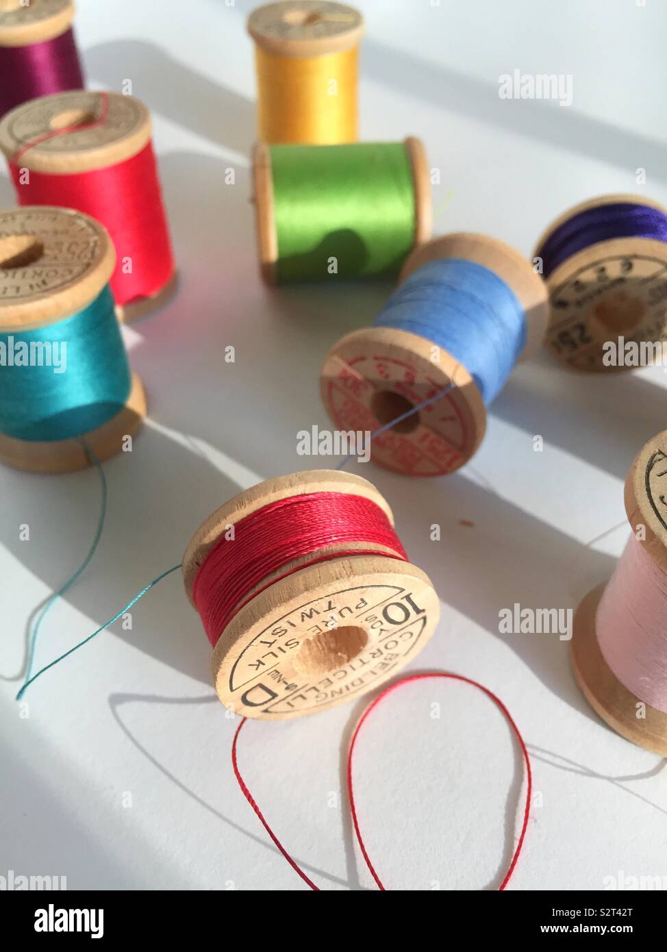 Detail of vintage wooden spoons of multi colored thread on a white background - Smartphone Captured Stock Image