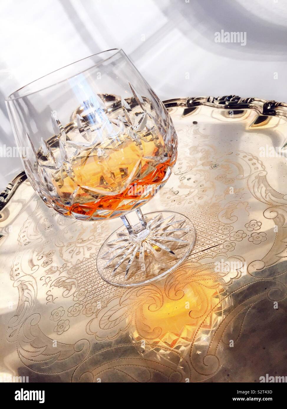 Close up of a crystal glass snifter of cognac on a polished silver tray
