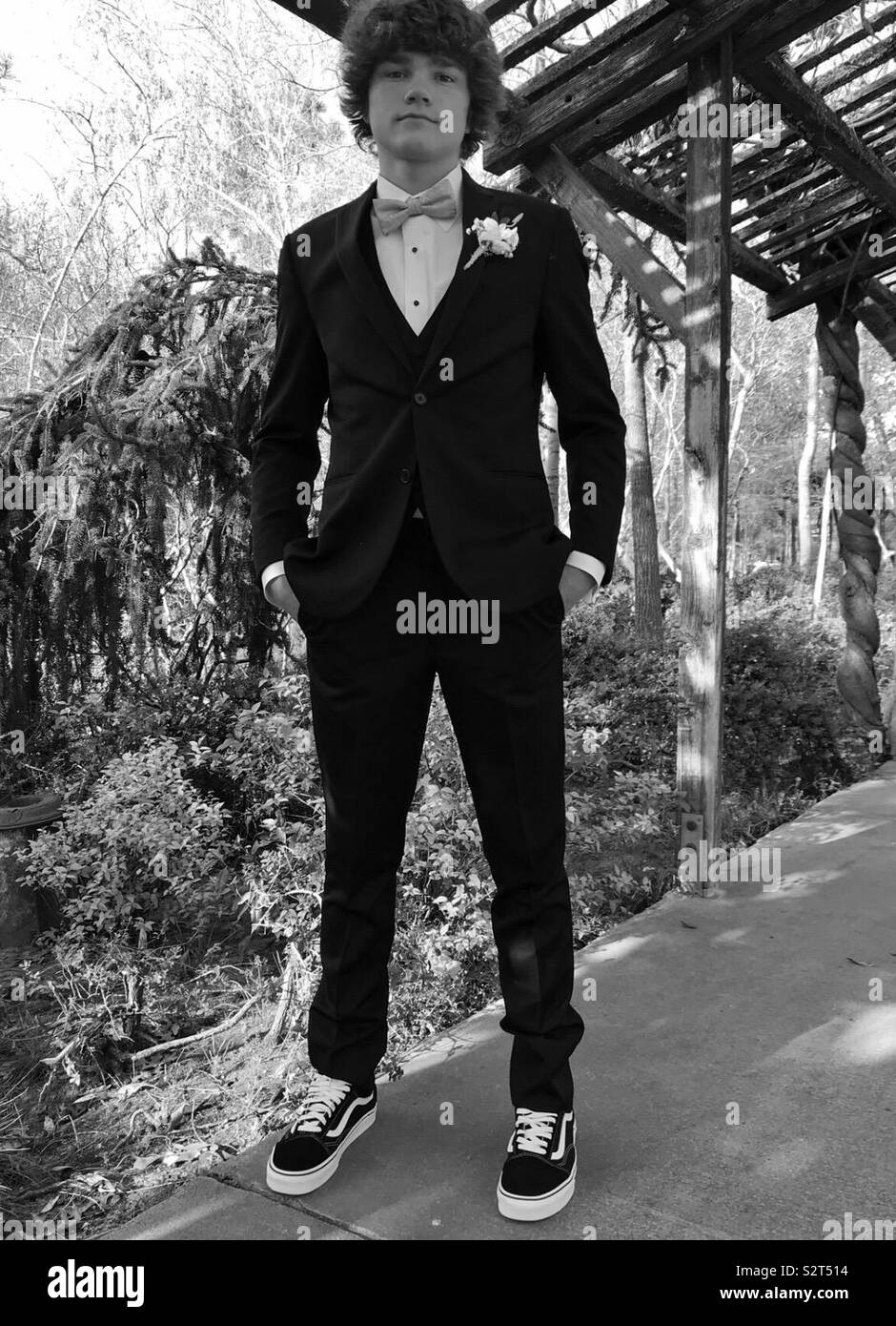 Prom. Boy in tuxedo standing in archway with hands in pocket wearing vans  tennis shoes. Nature. Flowers bushes in background. Black and white picture  Stock Photo - Alamy