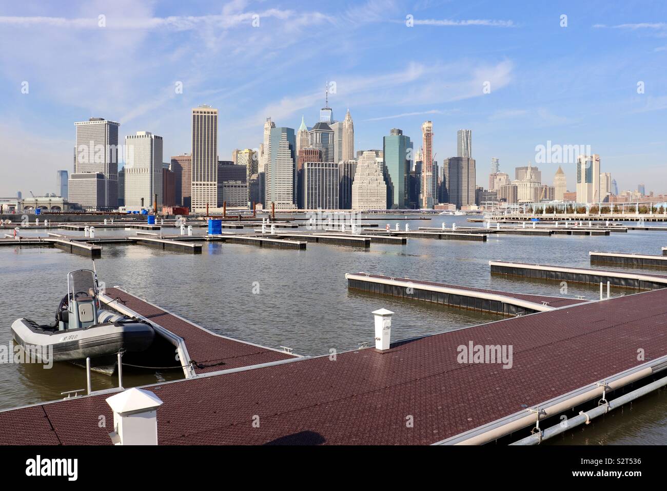 Small boat moored at jetty with New York City skyline as backdrop Stock Photo