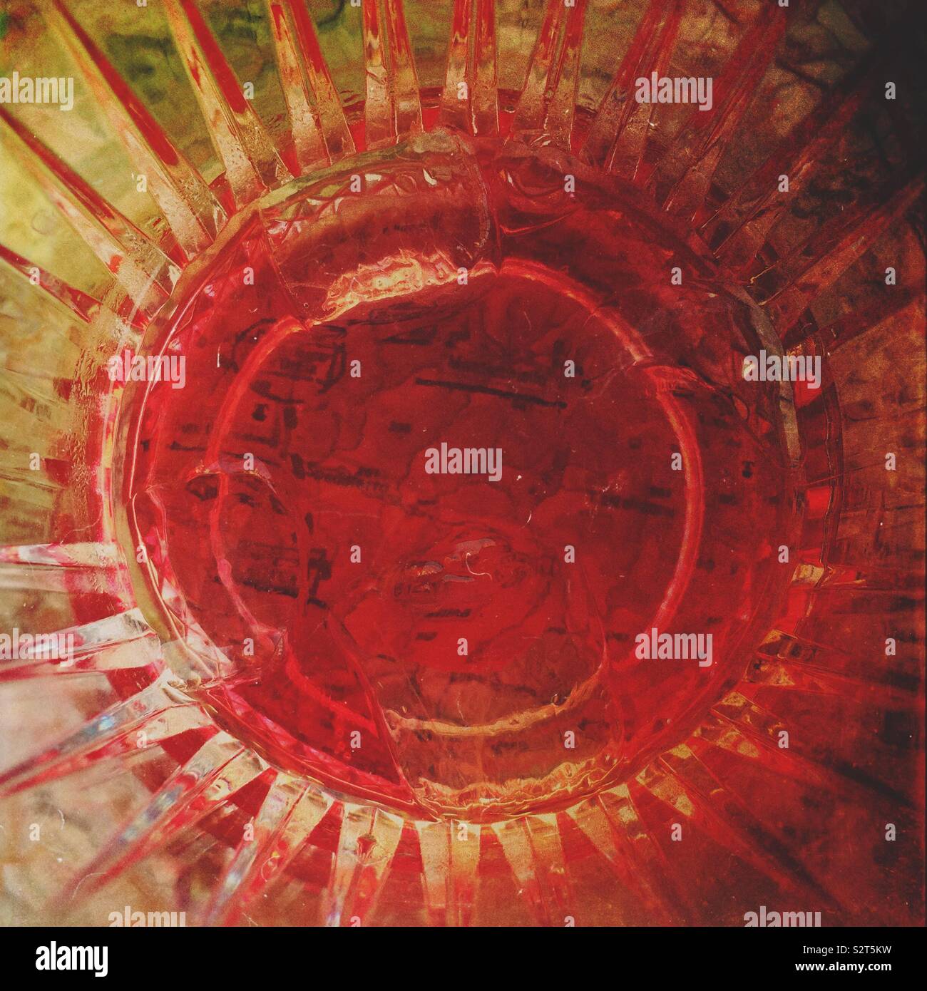 An abstract radiating circular pattern of a bottom of a drink glass in red Stock Photo