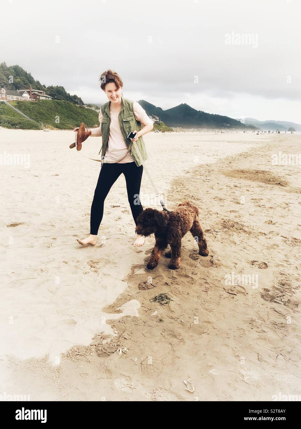 Summer photo of a woman walking her dog on Cannon Beach, OR- - Smartphone Captured Stock Image