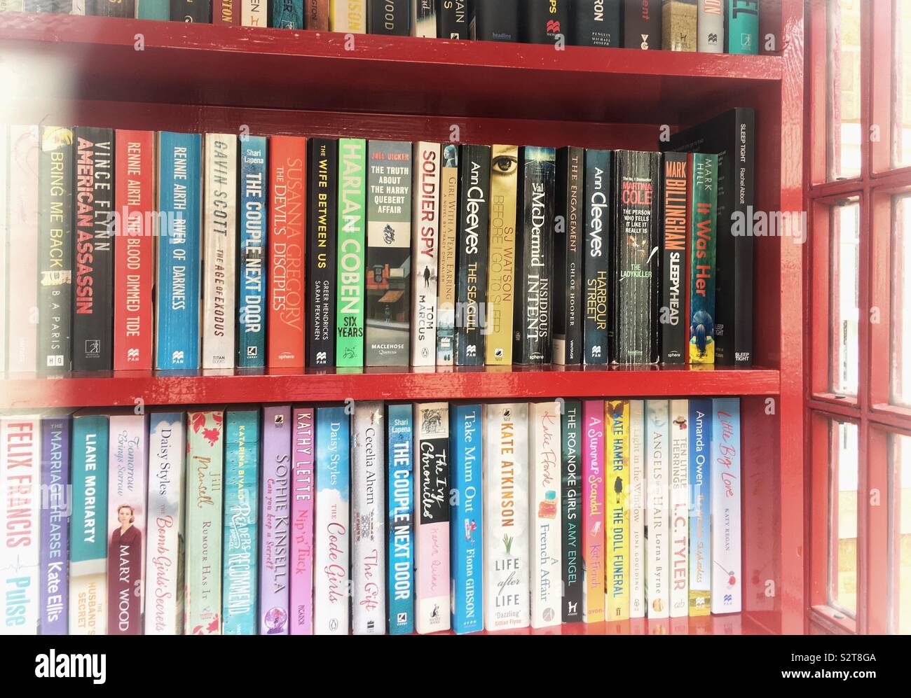 Shelves of paperback books in an old red telephone box, converted into a mini library; Collingtree, UK - Smartphone Captured Stock Image