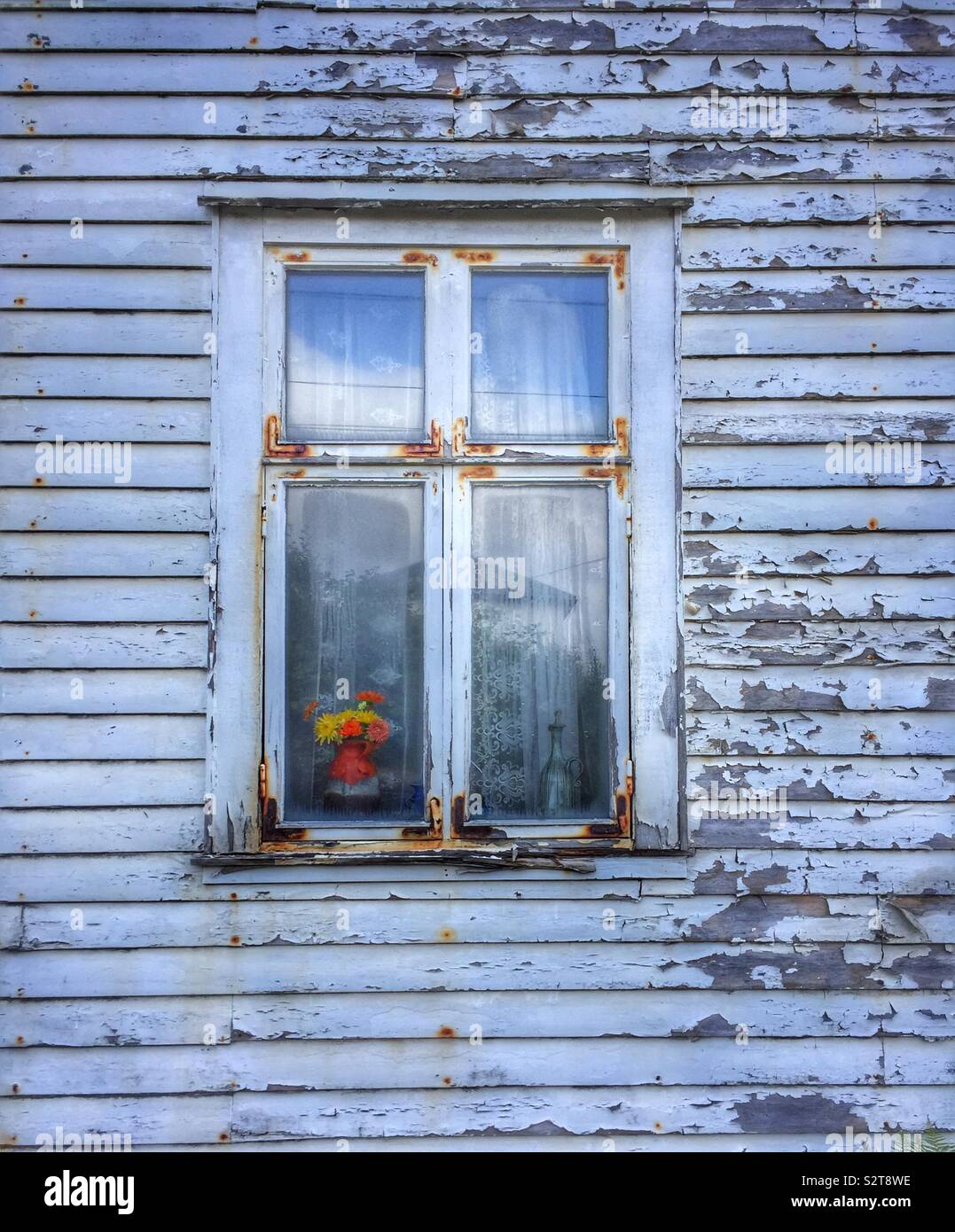 A vase of flowers in the window of an old wooden house Stock Photo