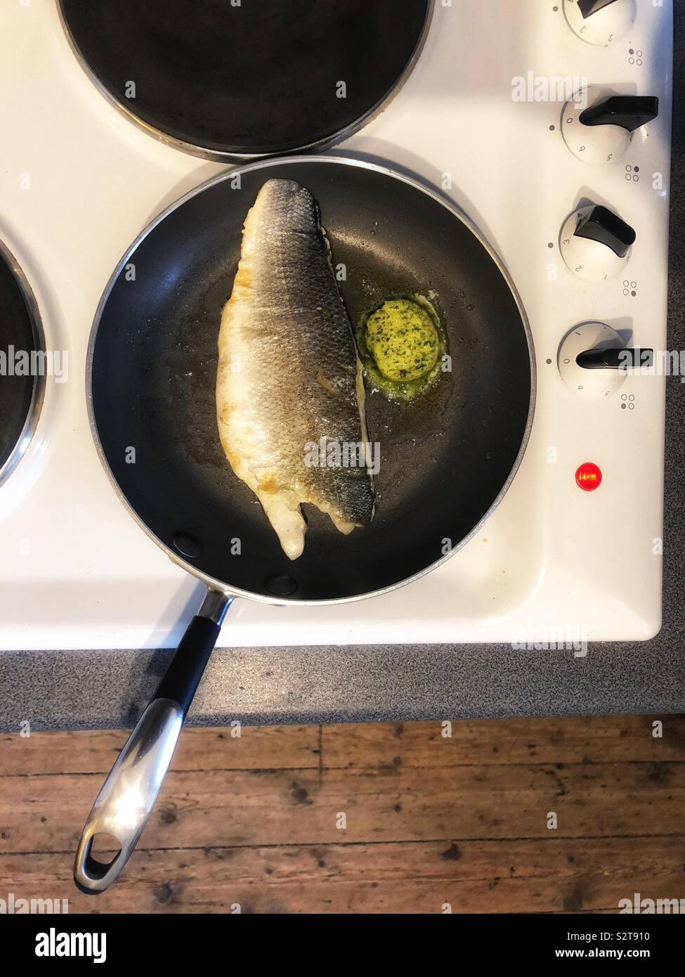 Sea bass fish fillet in frying pan with garlic butter - Smartphone Captured Stock Image