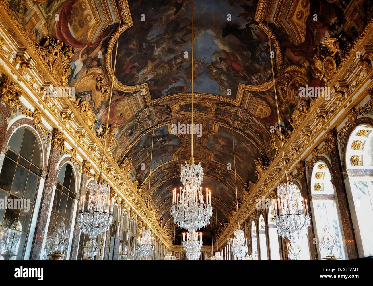 Enormous vaulted painted ceilings and crystal chandeliers of the Hall of Mirrors in Versailles Palace Stock Photo