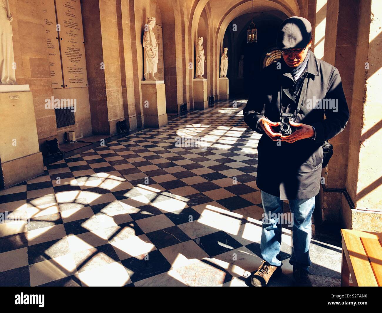 Middle aged man using old vintage film camera inside Palace of Versailles - Smartphone Captured Stock Image