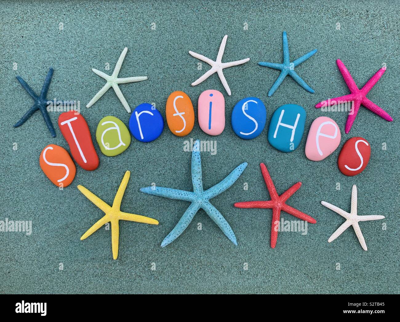 Starfishes text composed with colored sea stones over green sand - Smartphone Captured Stock Image