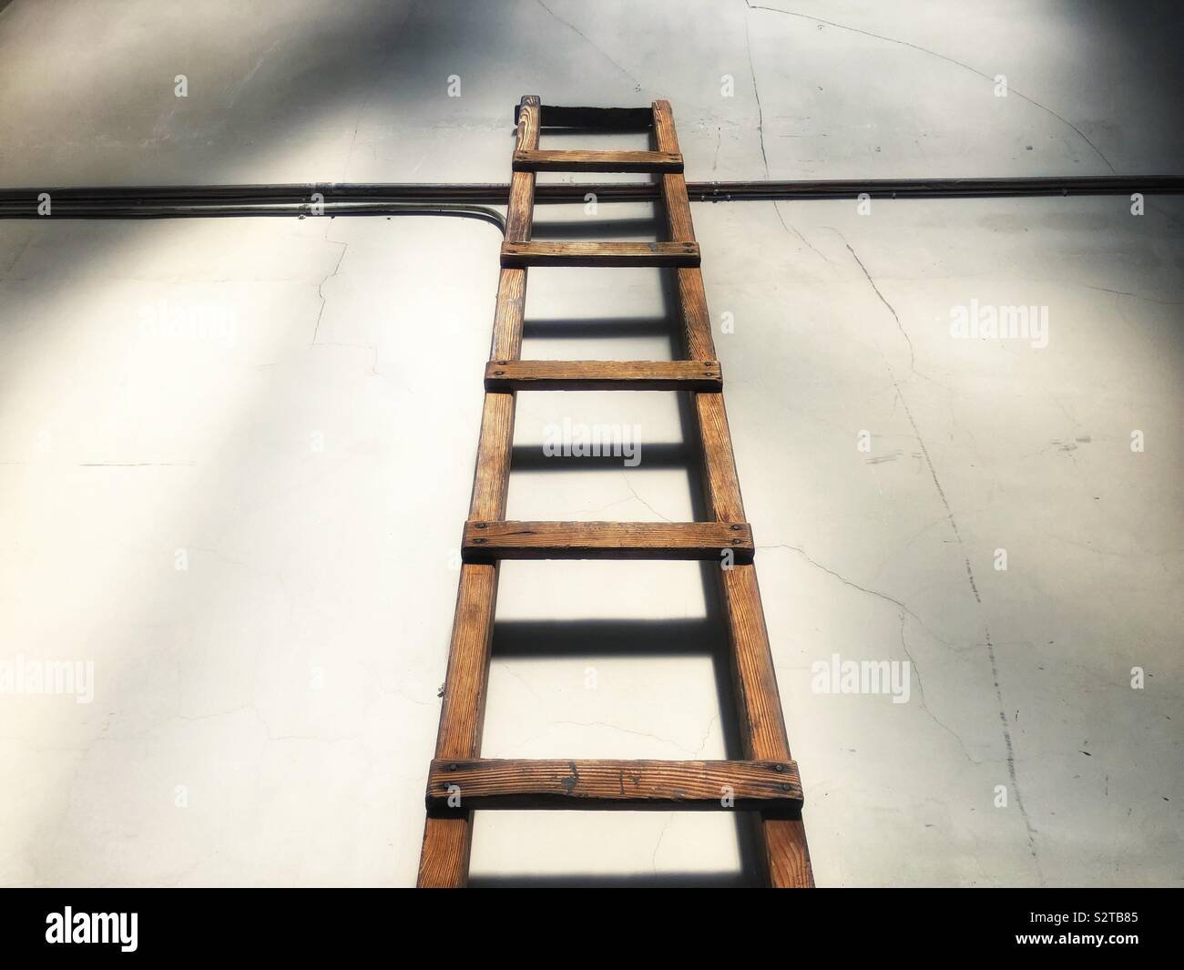 Wooden ladder leaning against internal wall - Smartphone Captured Stock Image