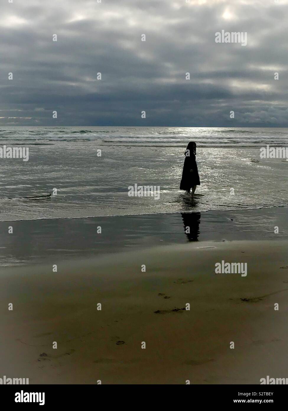 Silhouette of caped figure at edge of Pacific Ocean- Cannon Beach, July - Smartphone Captured Stock Image