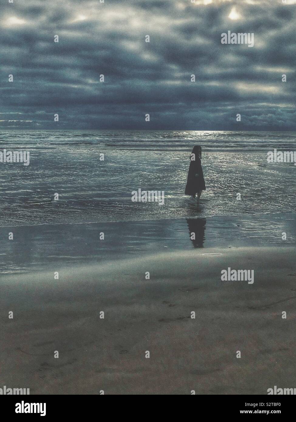 Solitary figure standing near edge of Pacific Ocean at Cannon Beach in July - Smartphone Captured Stock Image