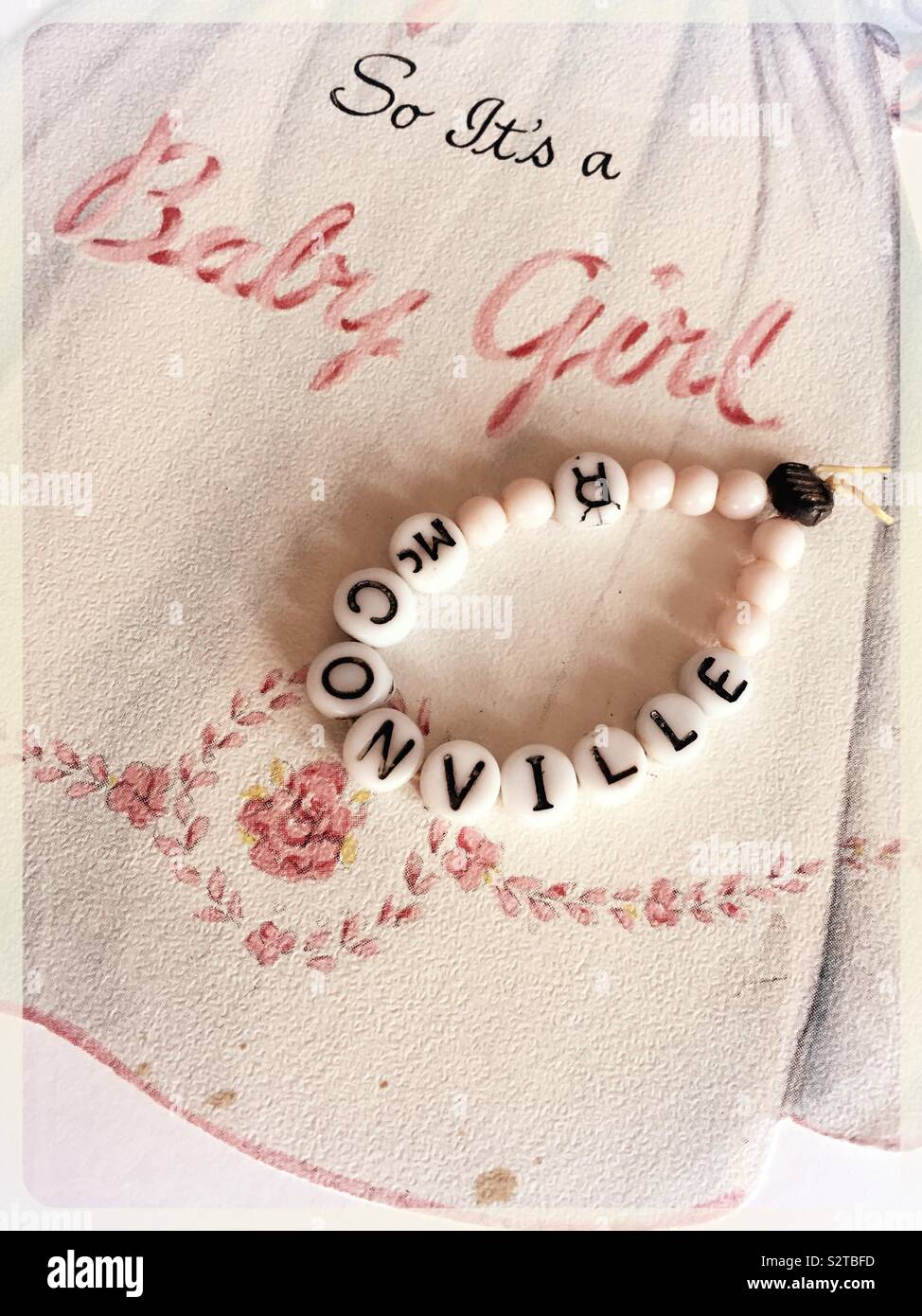 Vintage beaded identification bracelet for a newborn baby girl in a hospital nursery and a retro birth announcement card, 1940s - Smartphone Captured Stock Image