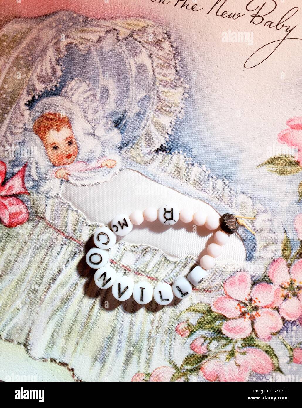 Vintage beaded identification bracelet for a newborn baby girl in a hospital nursery and a retro birth announcement card, 1940s - Smartphone Captured Stock Image