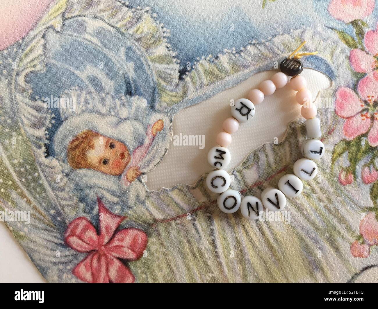 Vintage beaded identification bracelet for a newborn baby girl in a hospital nursery and a retro birth announcement card, 1940s - Smartphone Captured Stock Image