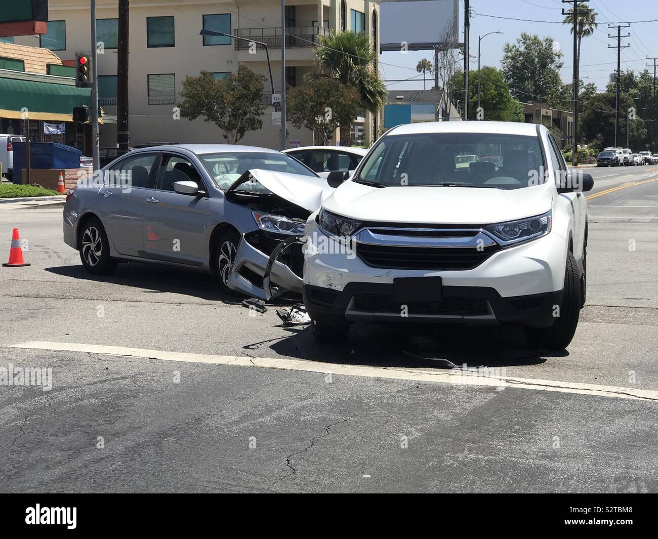 Two modern vehicles involved in a traffic accident are shown in a city road intersection during the day. - Smartphone Captured Stock Image